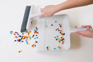 Homeopathy and Antibiotics Medicines being swept into a dustpan